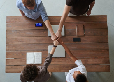 Team collaborating around a wooden table, overhead view